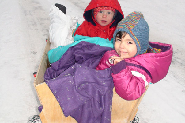 Die Tagespflegekinder fahren im Bollerwagen durch den braunschweiger Schnee.